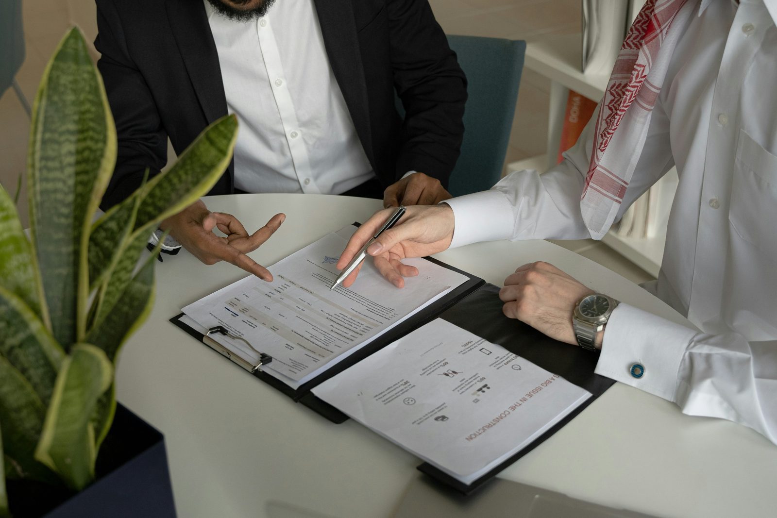 Two businessmen reviewing and signing papers at a table