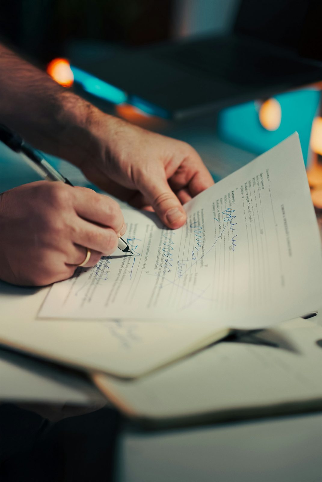 Hands signing a document in warm light