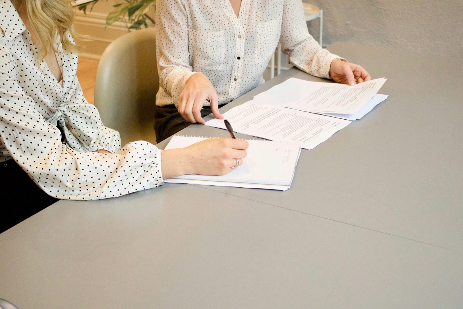 Two women at a table, one signing papers